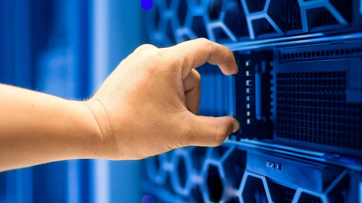 A technician's hand sliding a server into a rack in a data center